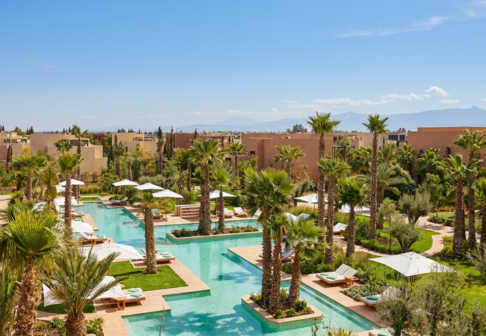 Elegant outdoor event with guests dining beside a large historic white building with ornate windows and greenery.