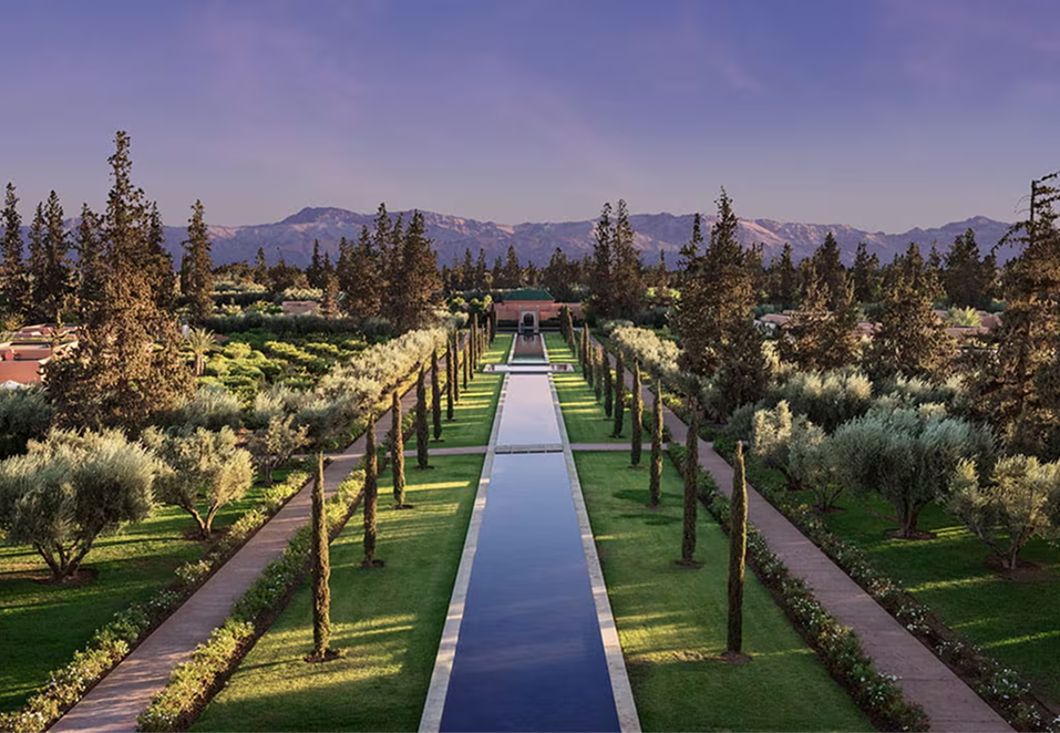 Elegant outdoor event with guests dining beside a large historic white building with ornate windows and greenery.