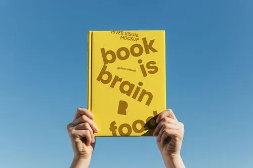 A person holding up a book that says book is brain food.