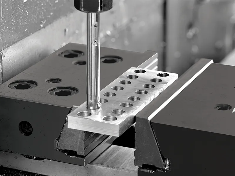 Precisiebewerking van metalen component met CNC-machine in zwart-wit.