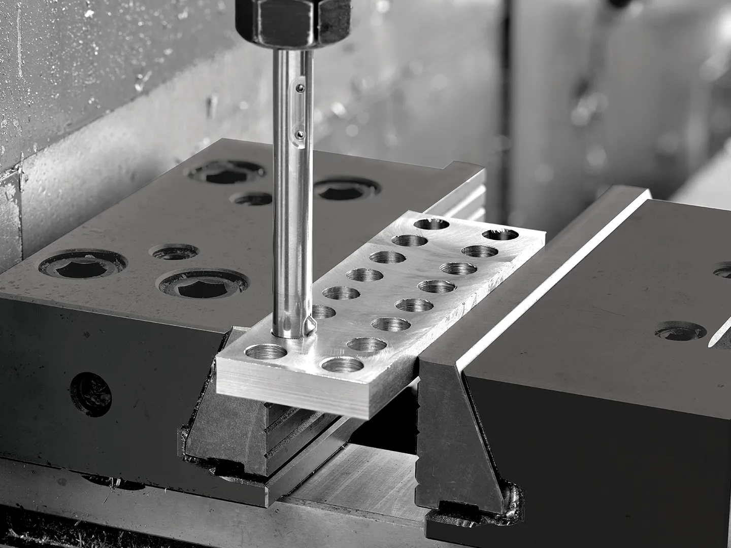 Precisiebewerking van metalen component met CNC-machine in zwart-wit.