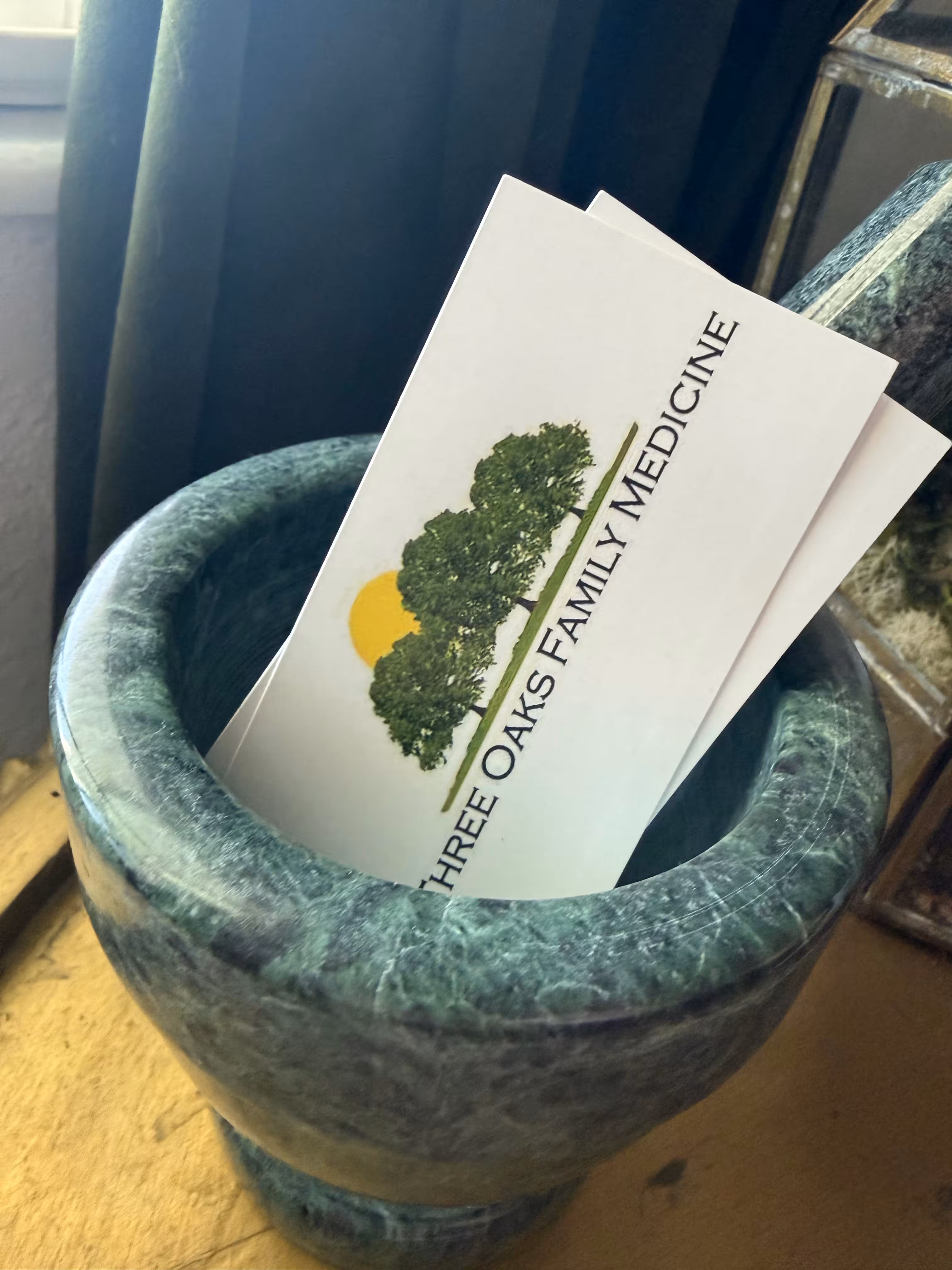 Business cards for Three Oaks Family Medicine placed inside a green marble mortar.