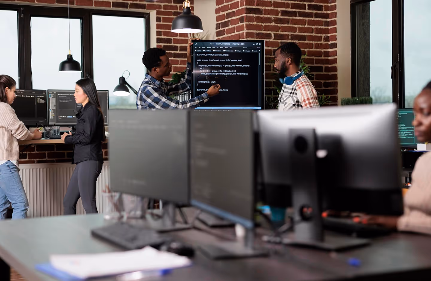 Team in technischer Arbeitsumgebung vor mehreren Monitoren