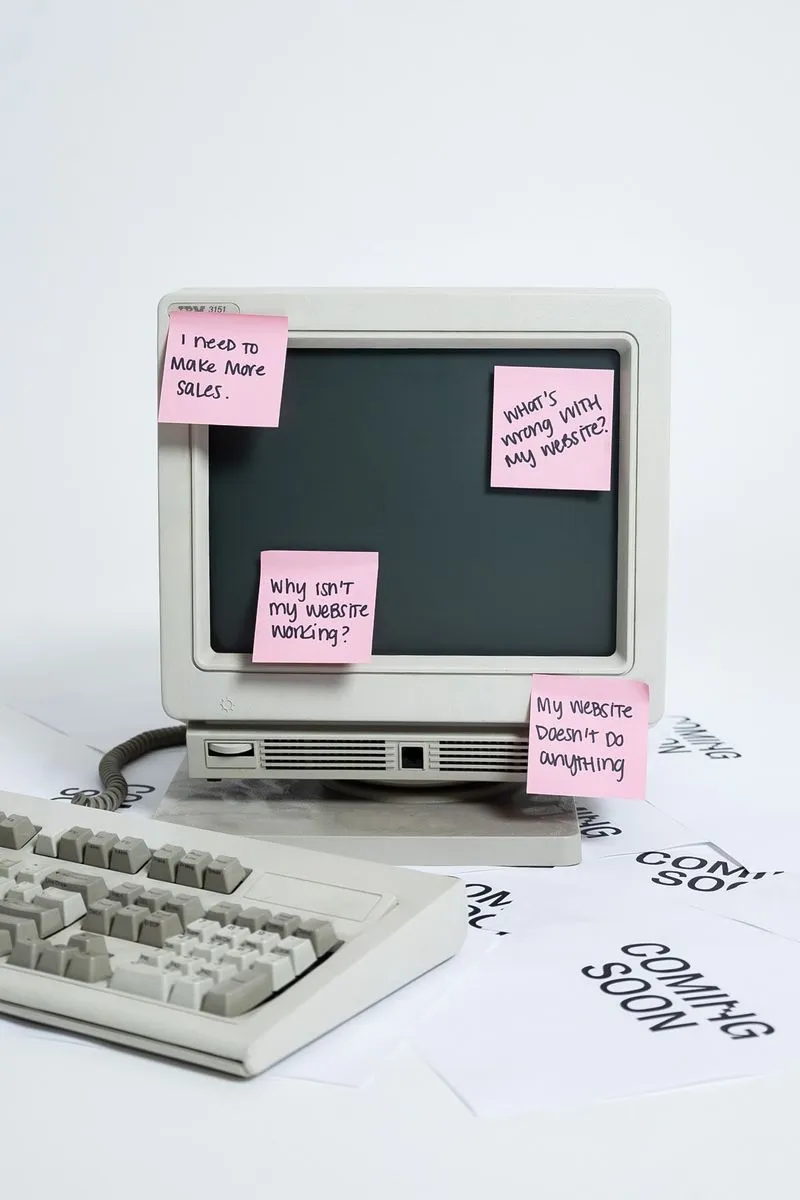 Retro computer covered in pink sticky notes that read "Why isn't my website working?" and "What's wrong with my website?"