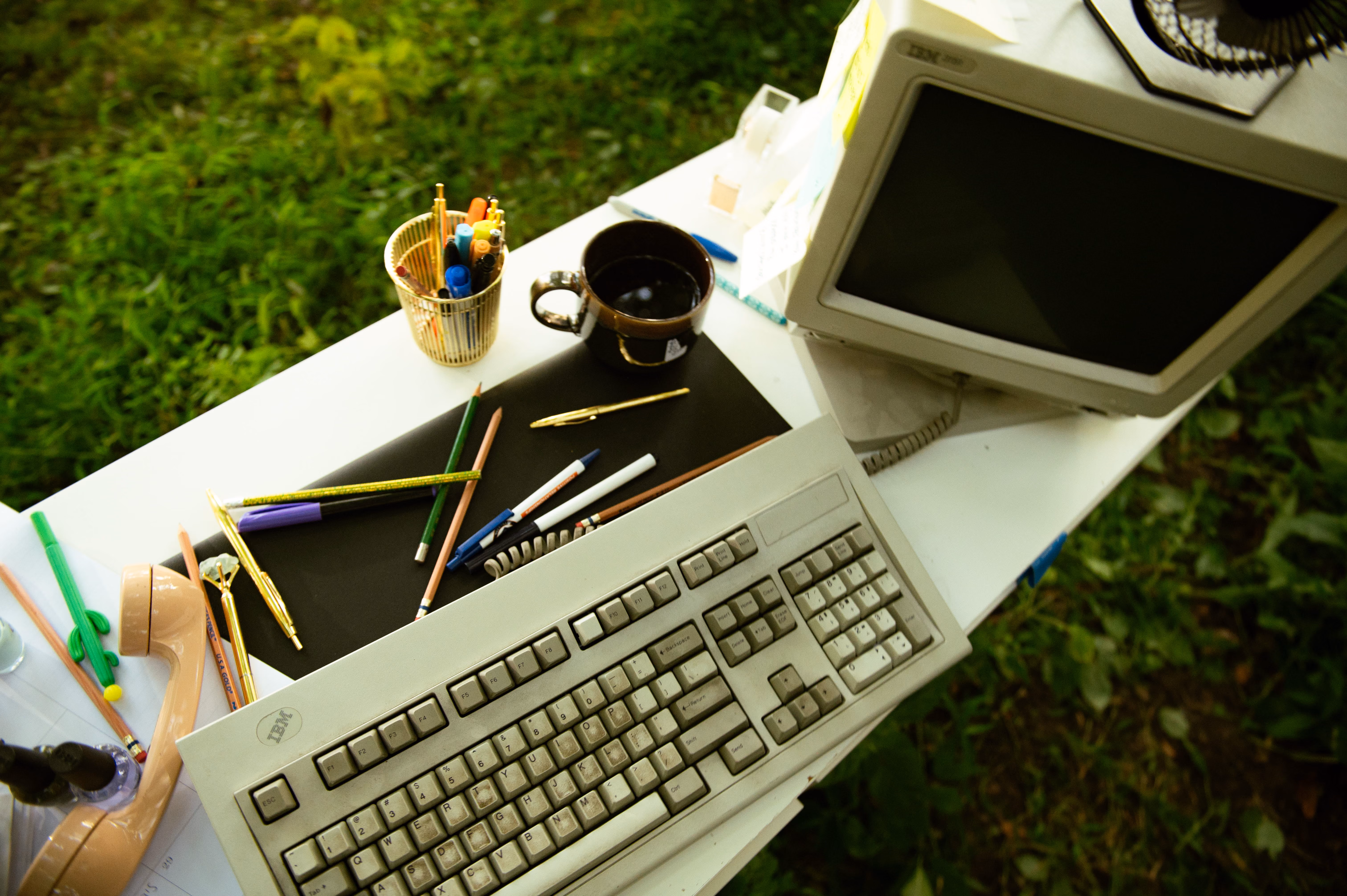 Vintage computer and keyboard on a white desk in the grass, from The Rebrand Lab's brand photoshoot