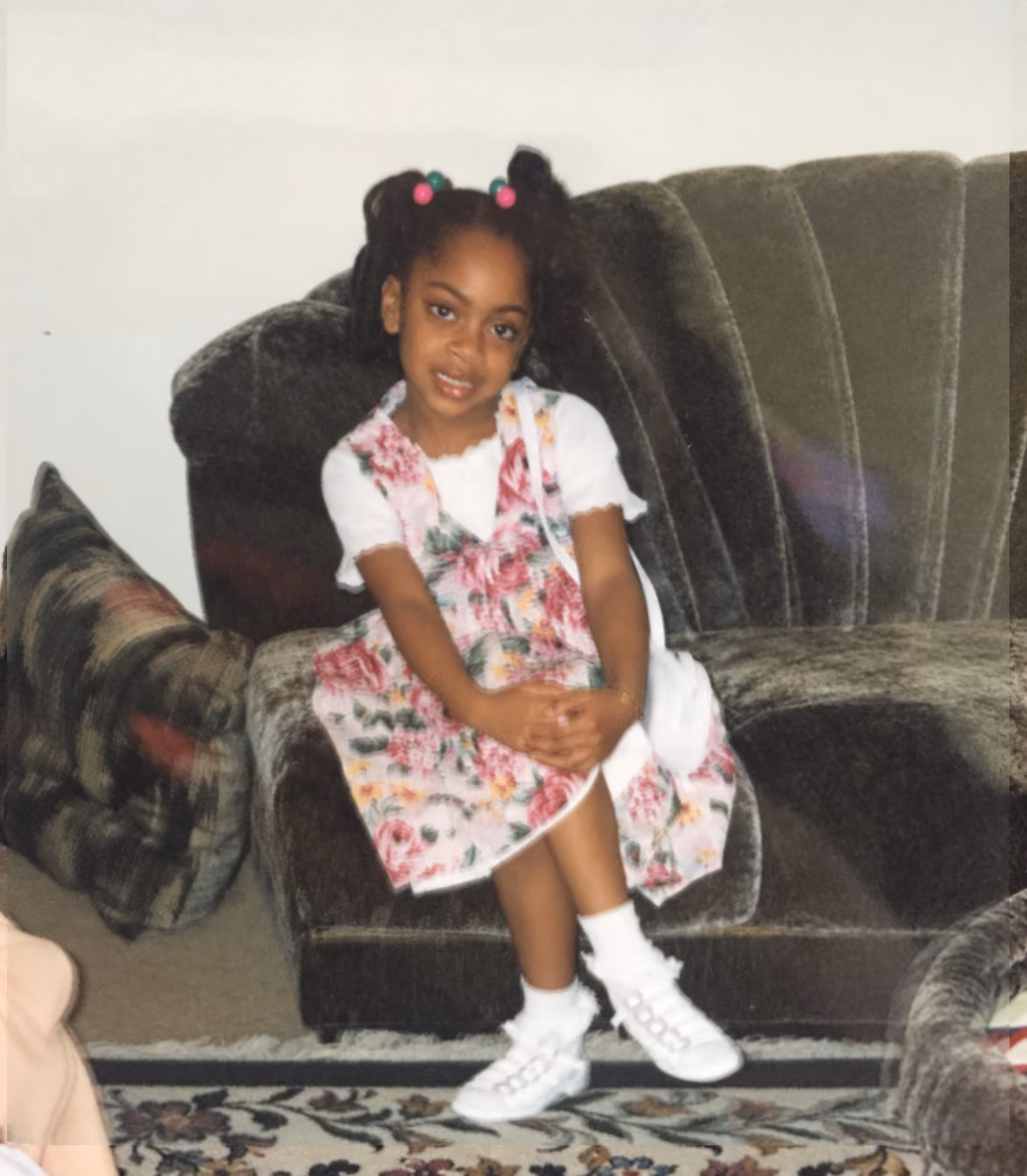 Domanique Taylor as a little girl, sitting in an armchair in a floral dress