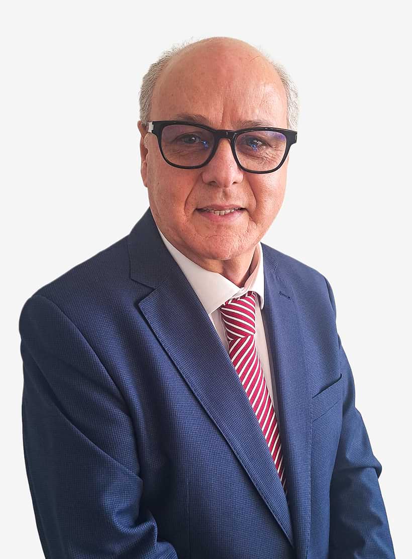 Homem de meia-idade com óculos, fato azul escuro e gravata às riscas vermelhas sorrindo debaixo de fundo branco.