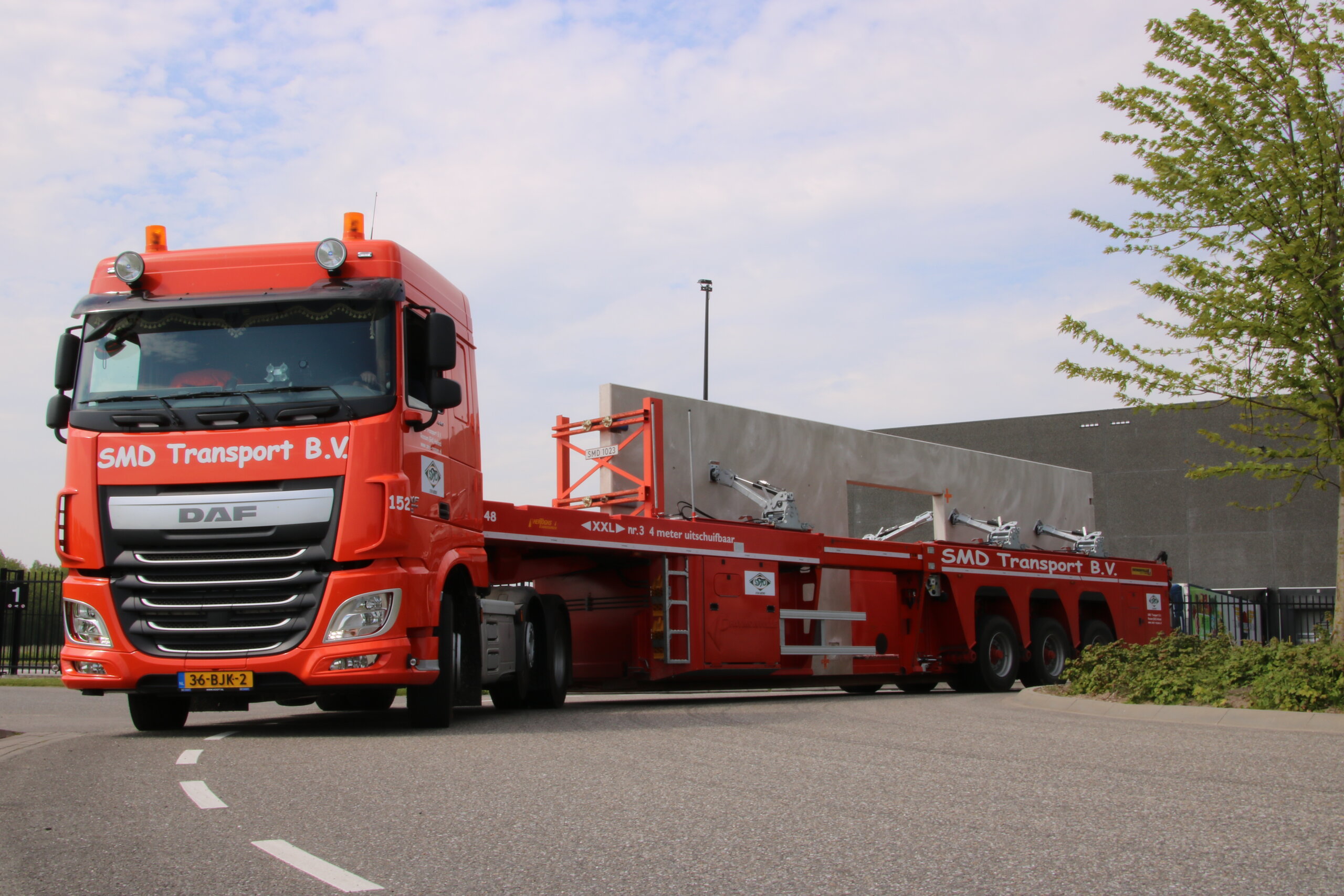 Oranje DAF vrachtwagen van SMD Transport B.V. met een lage oplegger op het bedrijfsterrein, circa jaren 2010.