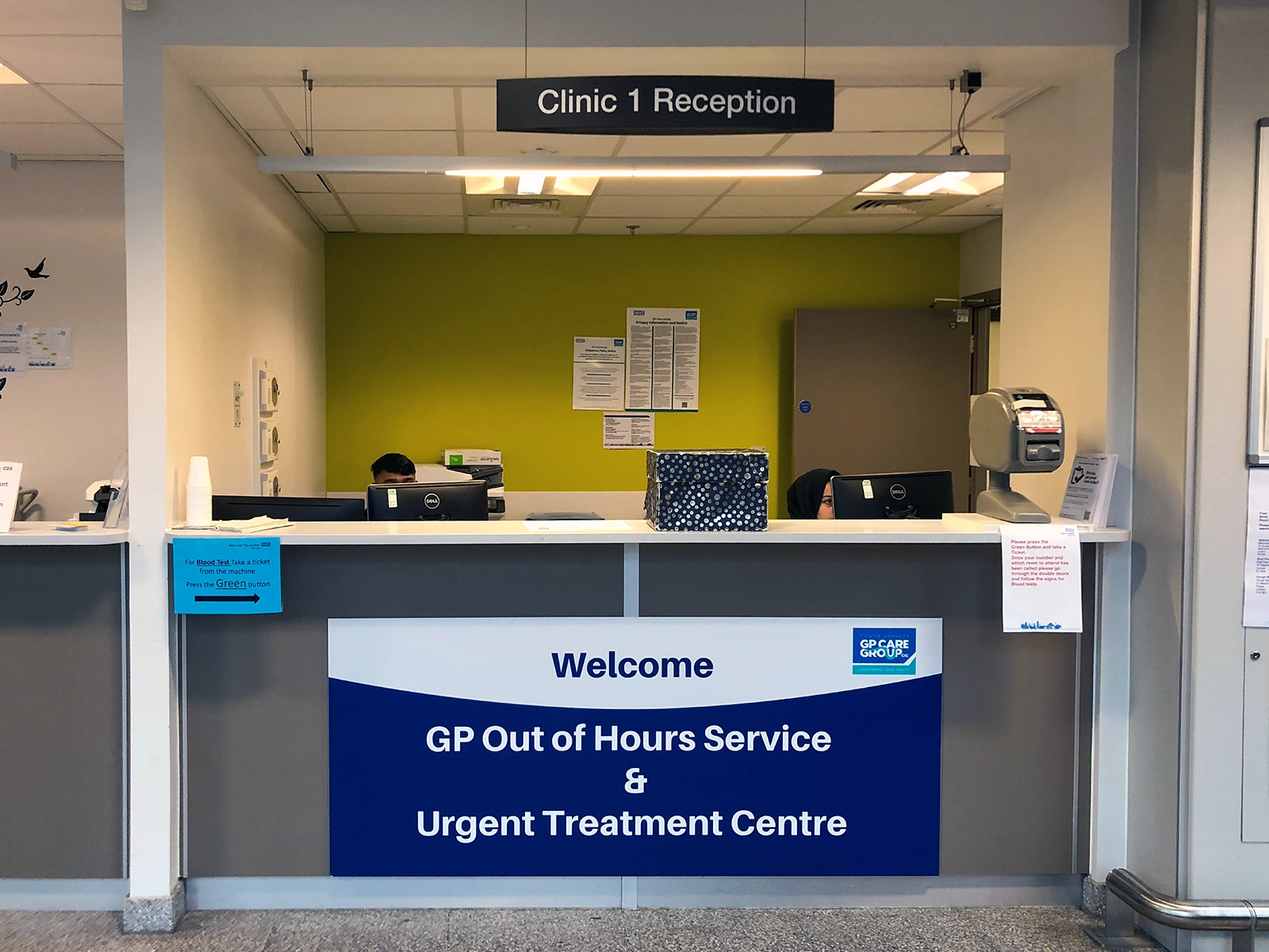 Reception desk in Clinic 1 with sign welcoming to GP Out of Hours Service and Urgent Treatment Centre.