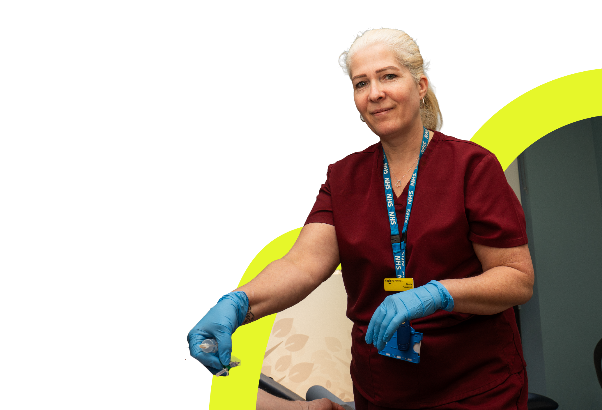 Healthcare worker in maroon scrubs and blue gloves preparing to administer an injection.