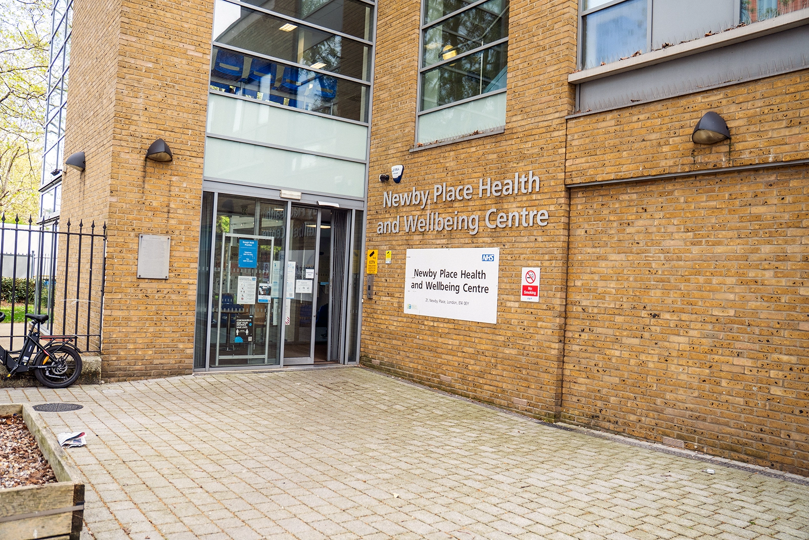 Entrance to Newby Place Health and Wellbeing Centre with glass doors and brick exterior walls.