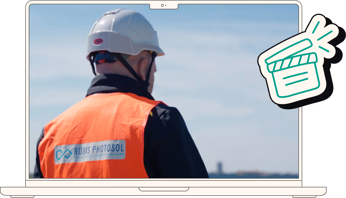 Employé portant un casque blanc et un gilet orange avec le logo Rubis Photosol, producteur d'énergie solaire, vu de dos devant un ciel bleu.