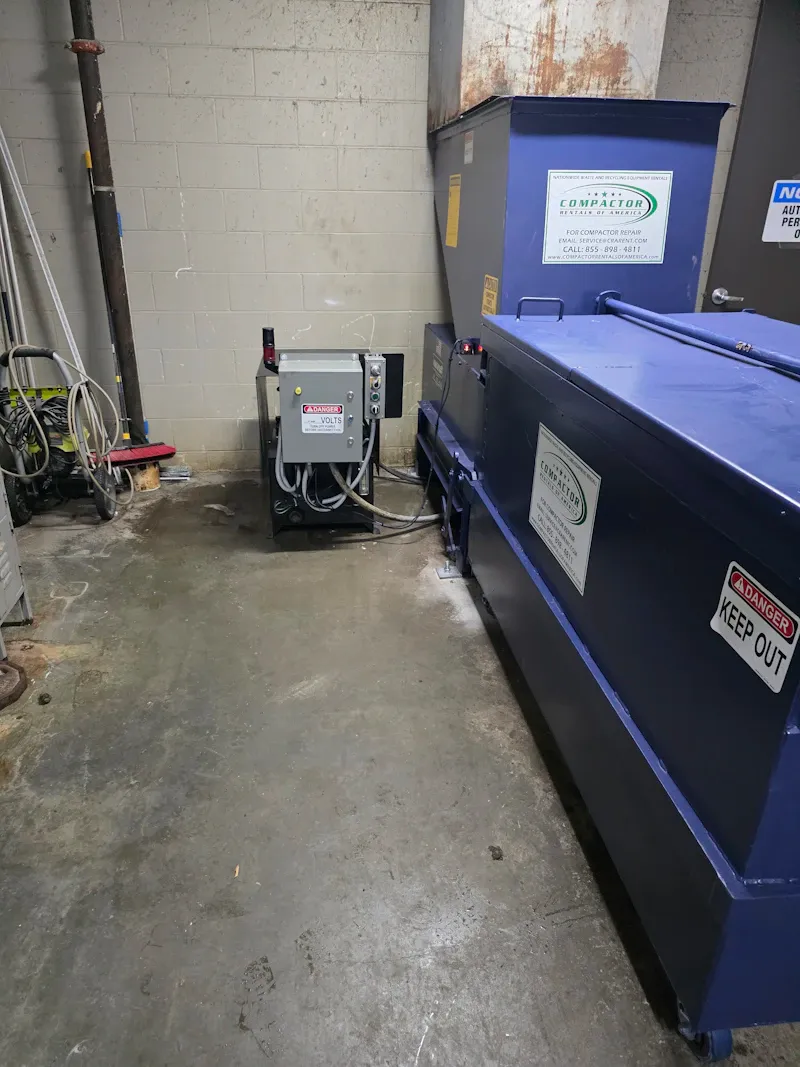 Compactor for heavy-duty shop waste management with electrical controls. Compactor, Danger High Volts, and Keep Out.