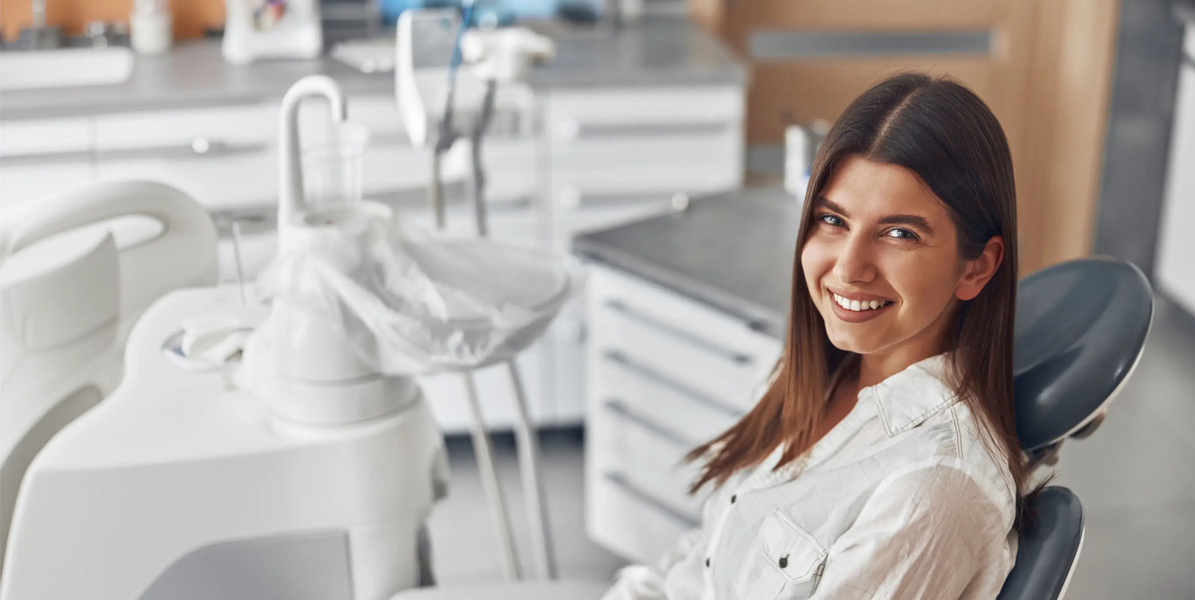 Smiling young woman sitting in a dental chair in a modern dental clinic.
