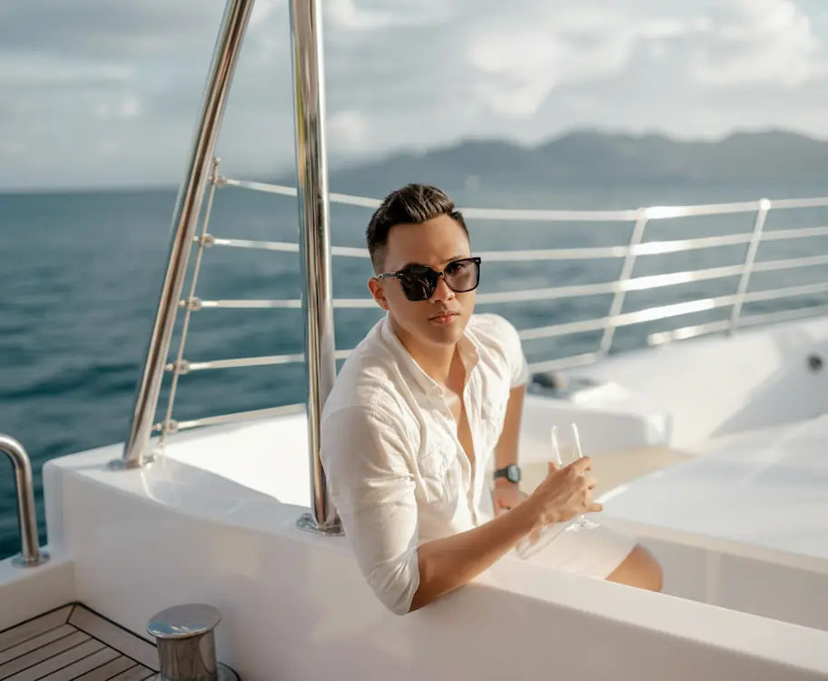 Hombre sentado en la cubierta de un yate tomando una copa