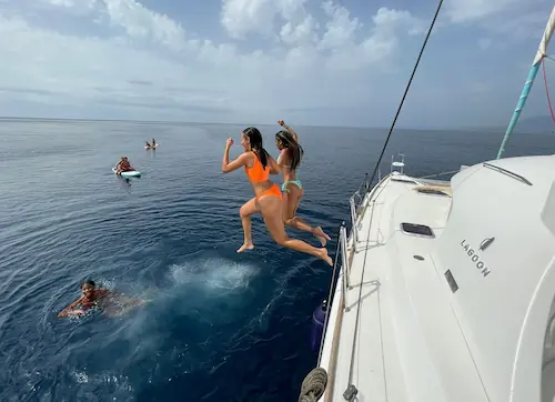 Mujeres saltando al mar desde un catamarán