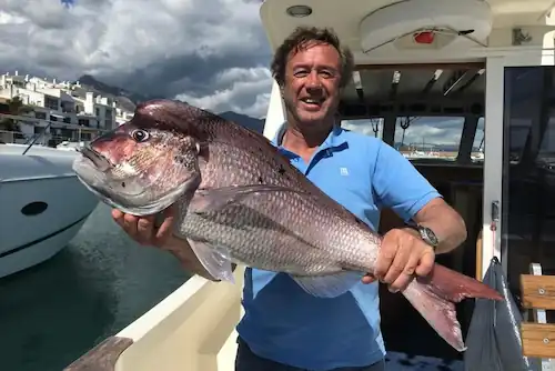 Hombre sosteniendo un pez en la Lancha Rodman 1250 Luna