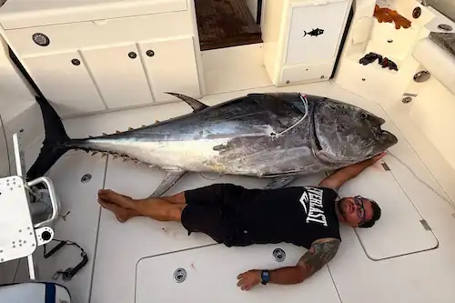 Hombre tumbado junto a un atún en la cubierta de la Lancha Sea Ray Sundancer 370 Mahi Mahi