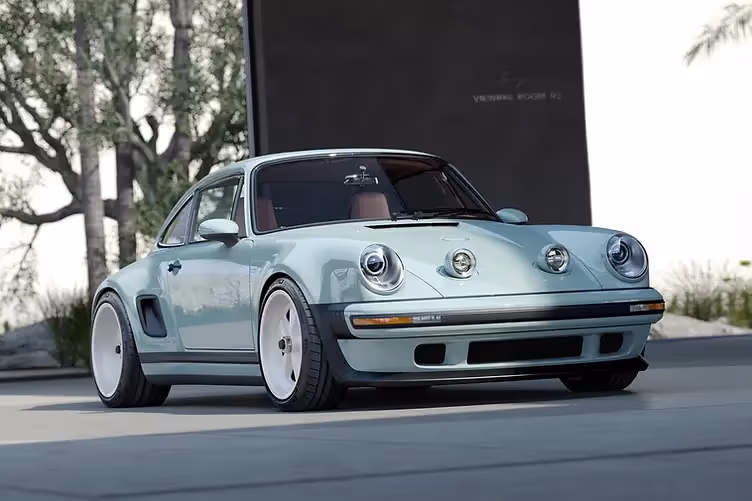 Singer’s latest reimagined 911 blends wide-body '80s looks with a 4.0L VVT flat-six, hybrid cooling, and F1-grade chassis tech from Red Bull. Front three quarter view with headlights popped up