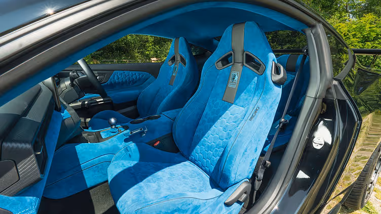 Interior view of the Clive Sutton CS800DH Mustang, featuring bright blue Alcantara Recaro seats, matching dashboard and door trim, a short-throw shifter, and digital instrument cluster with Mustang branding.