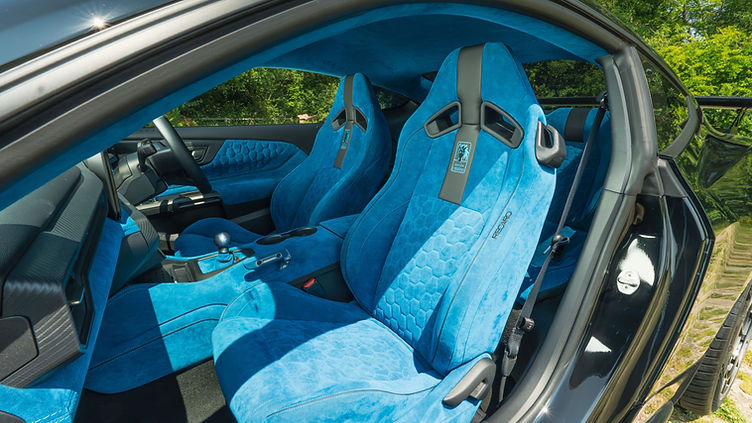 Interior view of the Clive Sutton CS800DH Mustang, featuring bright blue Alcantara Recaro seats, matching dashboard and door trim, a short-throw shifter, and digital instrument cluster with Mustang branding.