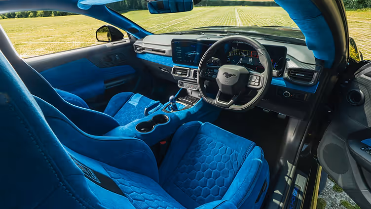 Interior view of the Clive Sutton CS800DH Mustang, featuring bright blue Alcantara Recaro seats, matching dashboard and door trim, a short-throw shifter, and digital instrument cluster with Mustang branding.