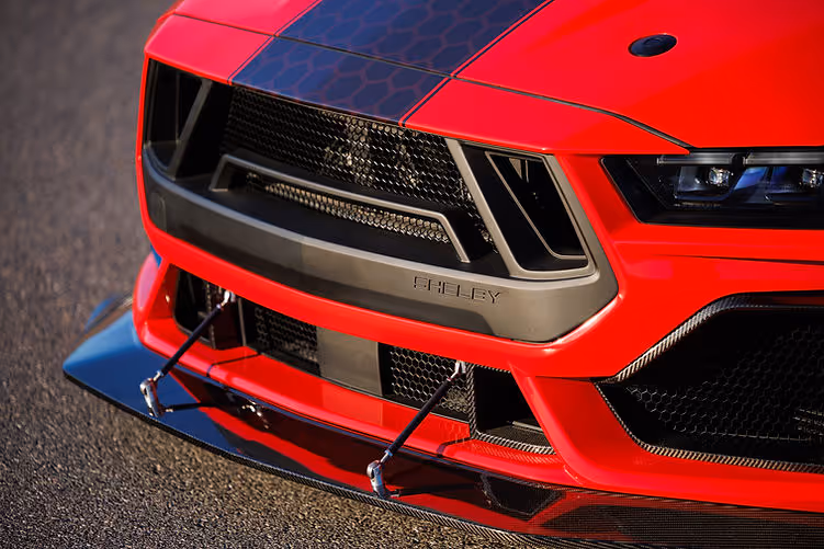Close-up of the Shelby Super Snake-R’s carbon front splitter with support rods, aggressive grille design and Shelby-branded bumper trim.