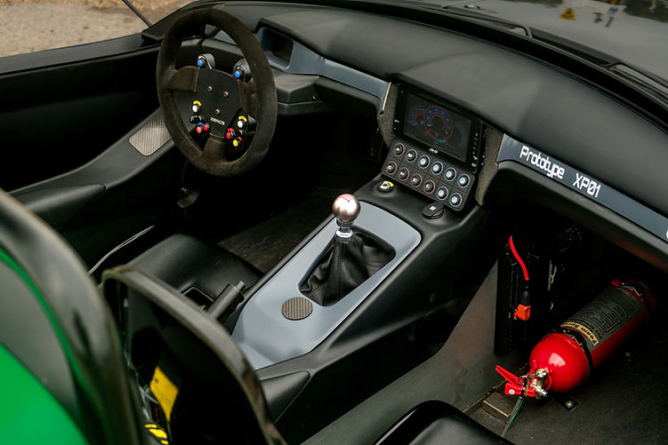 Zenos E10 RZ prototype interior showing race-style steering wheel, manual gear lever, and digital display.