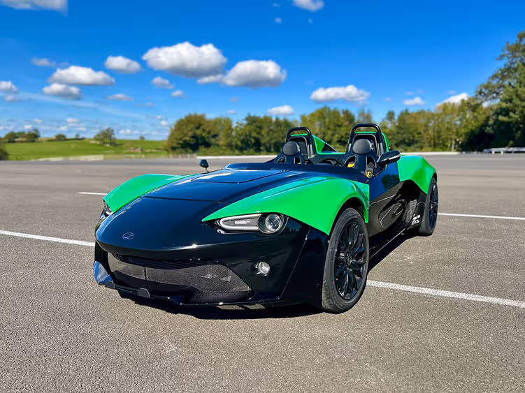 Front view of the Zenos E10 RZ under blue skies, showing its open-cockpit layout and aerodynamic design.
