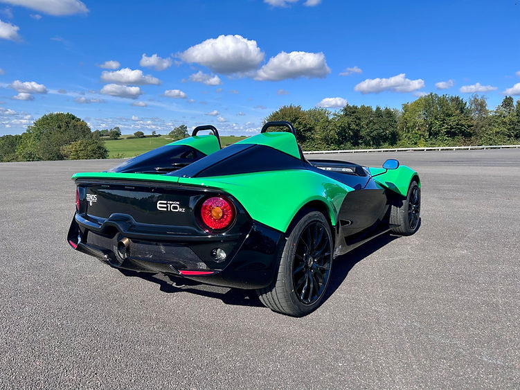 Rear view of the Zenos E10 RZ parked on tarmac, highlighting taillights, diffuser, and central exhaust.