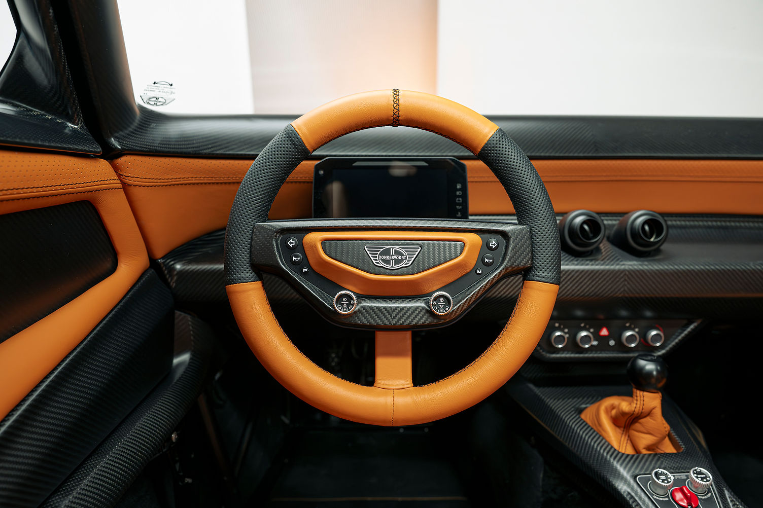Donkervoort P24 RS interior showing removable steering wheel with integrated controls and orange leather trim
