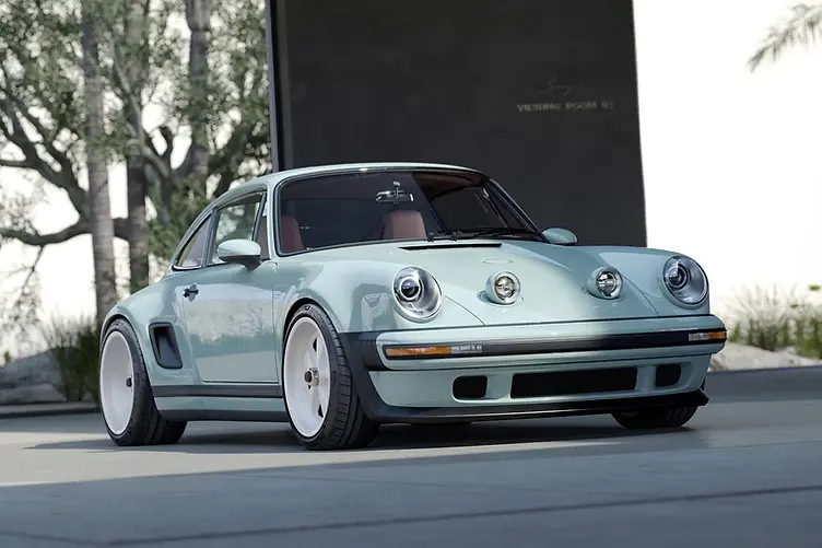 Singer's latest reimagined 911 blends wide-body '80s looks with a 4.0L VVT flat-six, hybrid cooling, and F1-grade chassis tech from Red Bull. Front three quarter view with headlights popped up