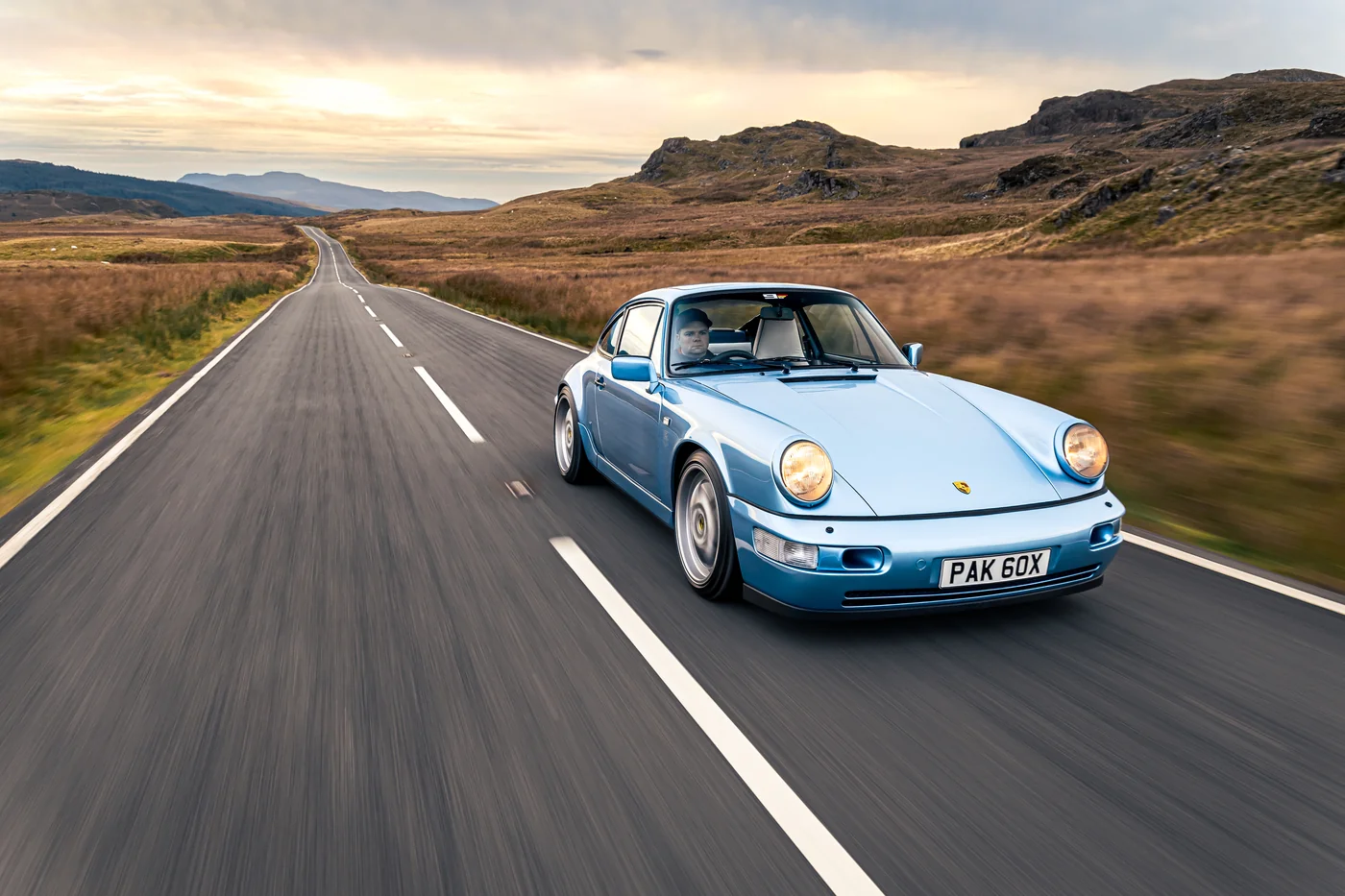 Porsche 964 Carrera 4 driving towards the camera at sunset on an empty road in Snowdonia