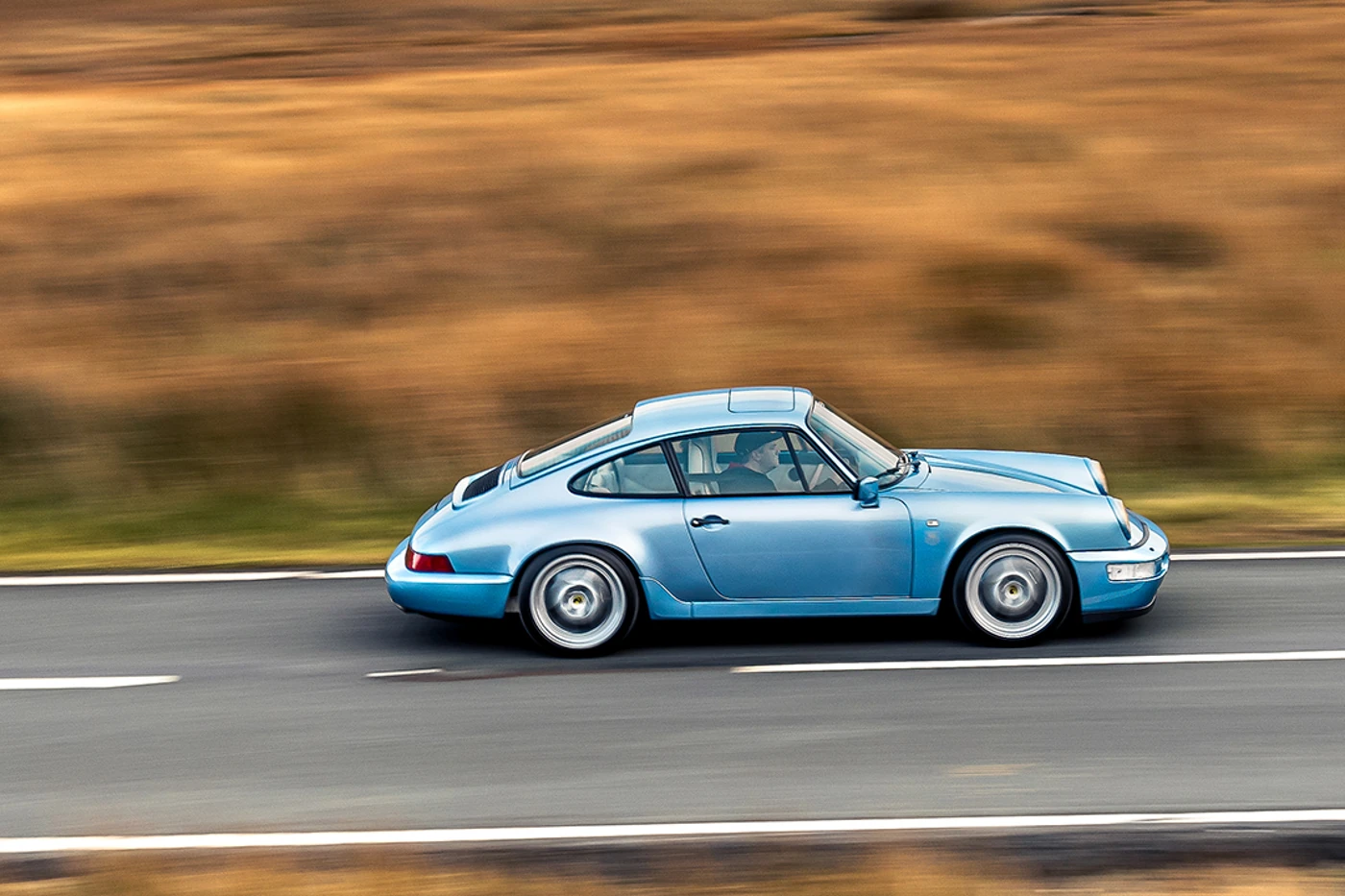 Porsche 964 Carrera 4 at speed, side-on, with the Eryri moorland blurred behind