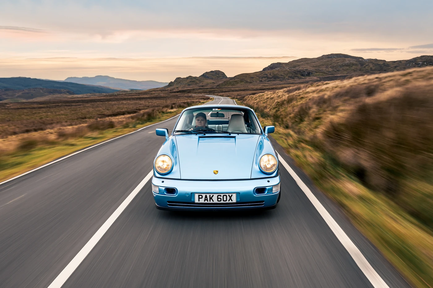 Porsche 964 Carrera 4 head-on at dusk, the road stretching away across the Eryri moorland