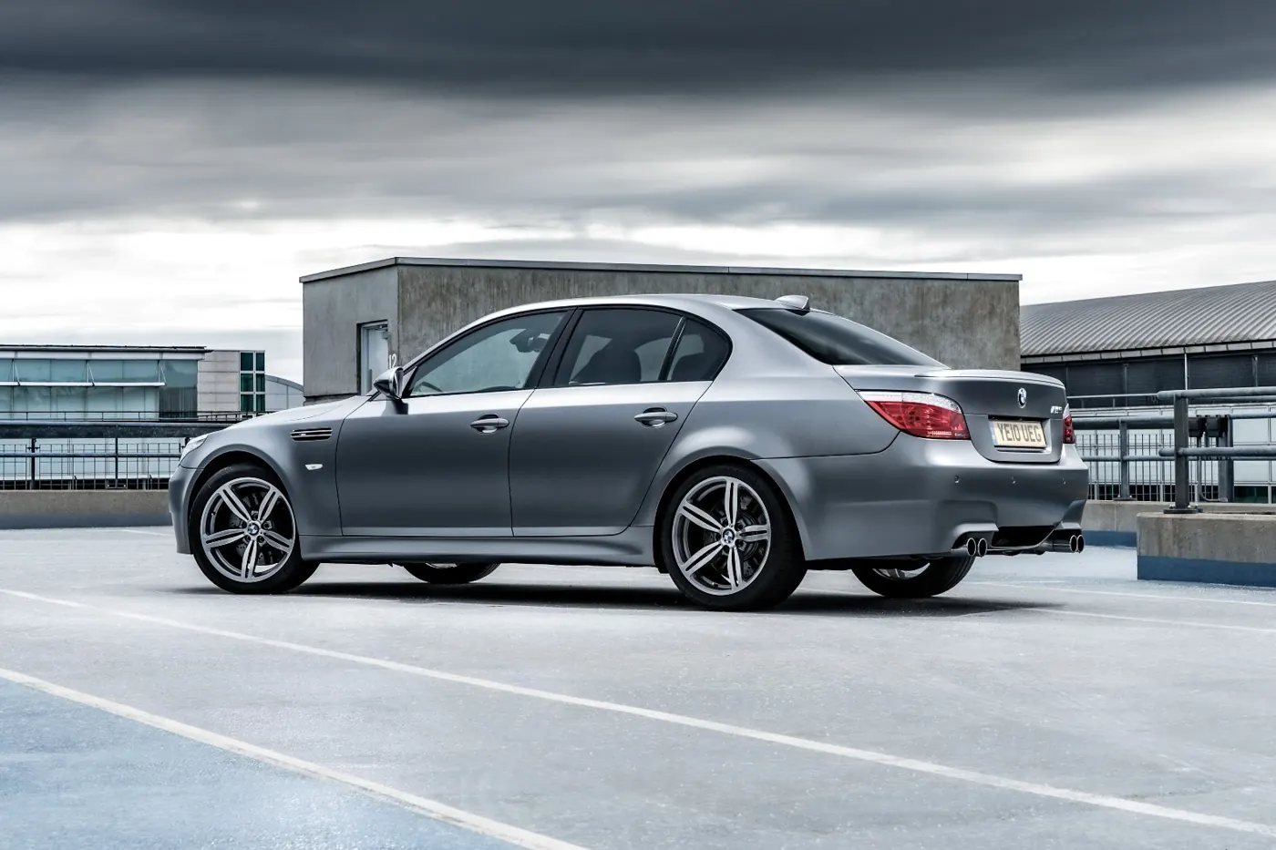 Silver grey metallic E60 BMW M5 review RUSH magazine rear static three quarter angle taken at a rooftop parking garage on an overcast day