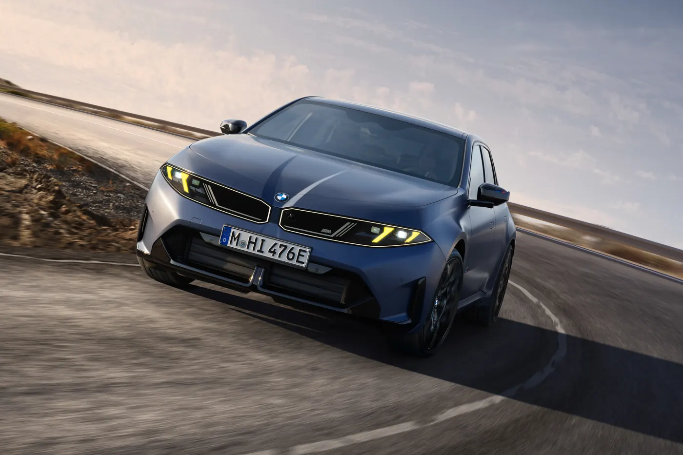 Blue BMW i3 M60 xDrive electric saloon side profile on a coastal road