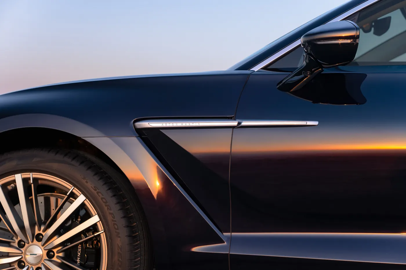 Close-up of the polished and satin metal side strake on the Aston Martin DBX GT front wing, above a Pirelli Scorpion Zero tyre