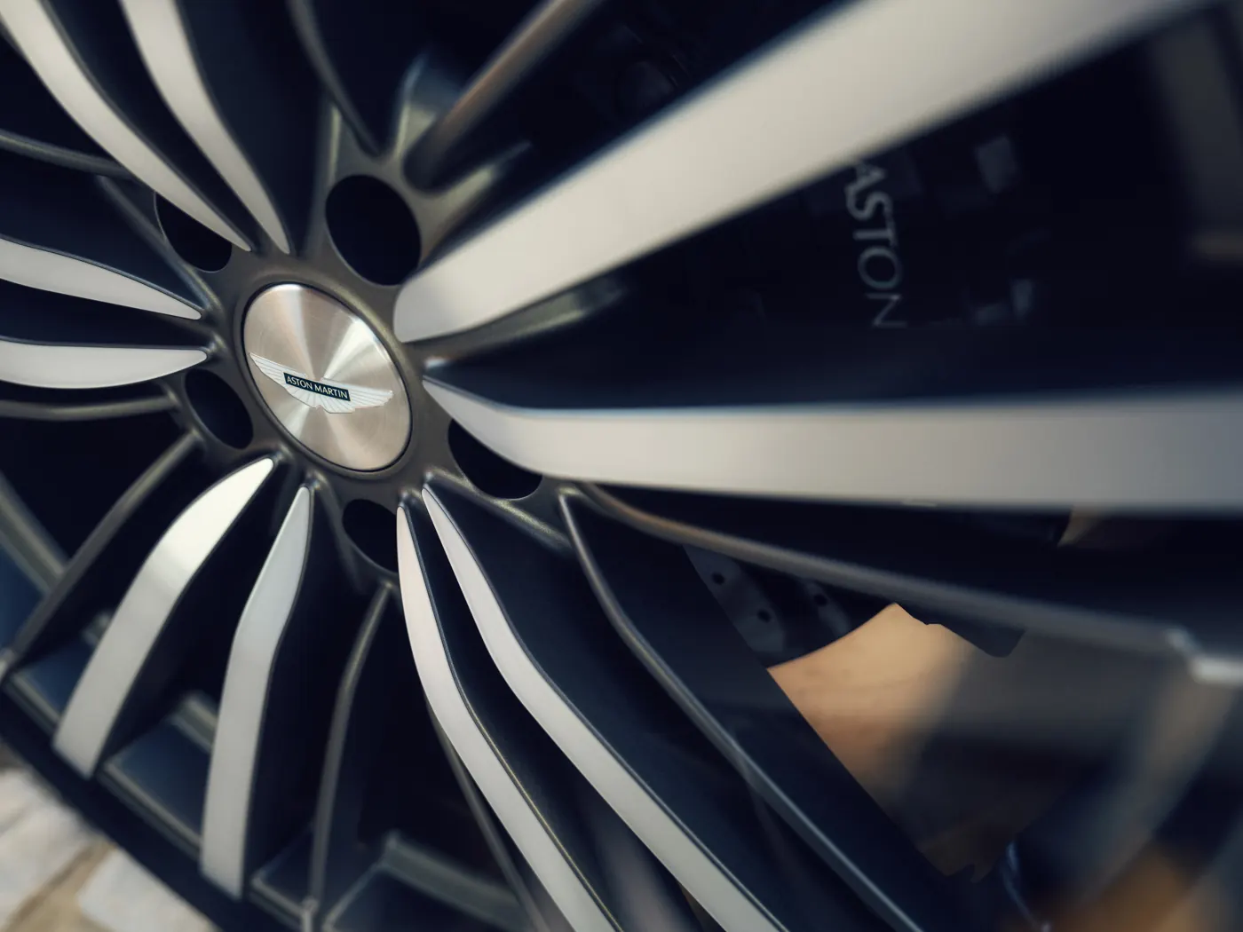 Close-up of an Aston Martin DBX GT forged multi-spoke wheel, with winged centre cap and brake calliper behind