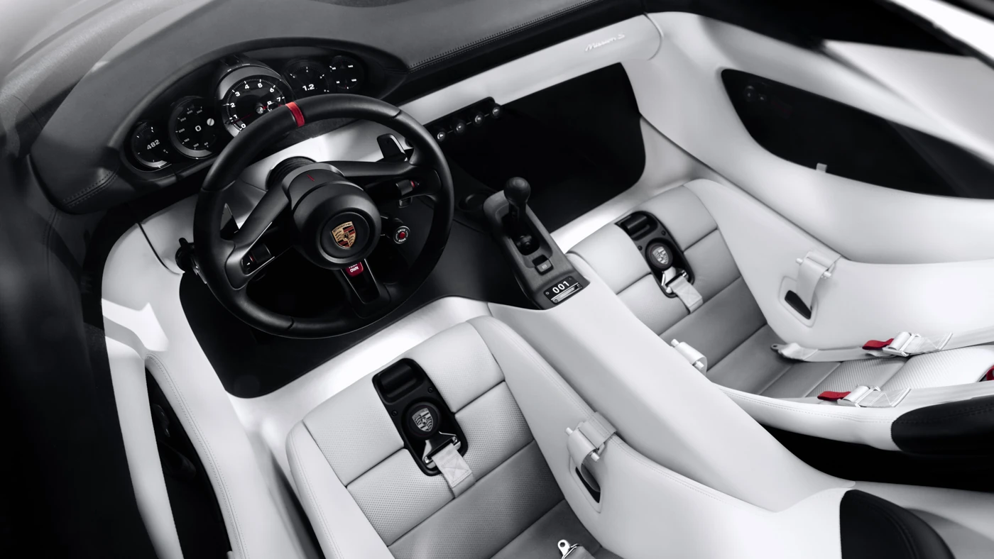 Mission S cockpit from above, with white leather bucket seats, black steering wheel and exposed gear linkage