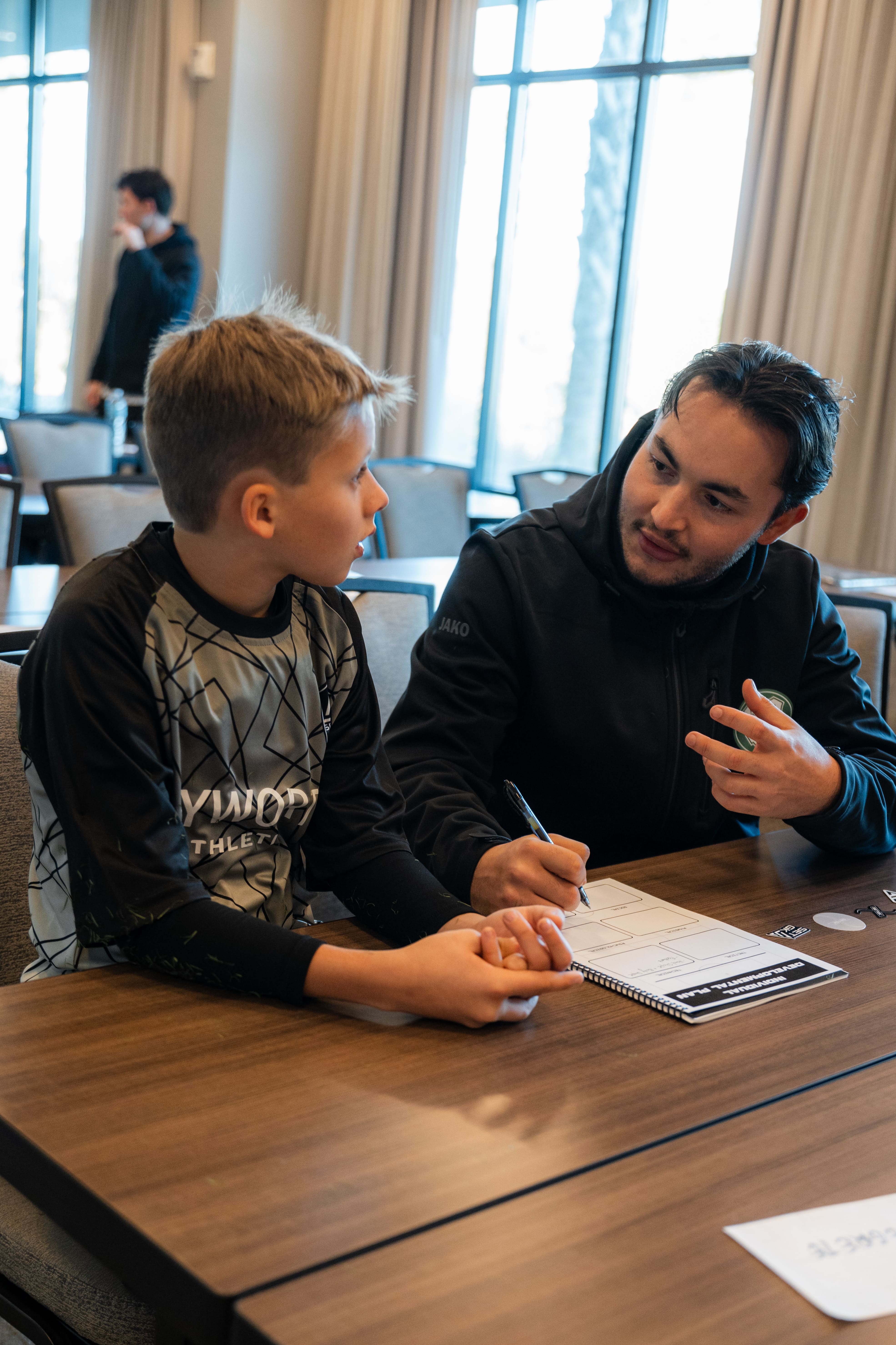 A professional goalkeeper mentoring a younger goalkeeper.