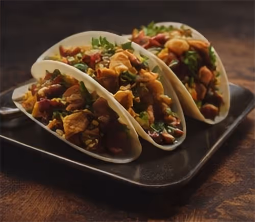 A plate of food with three tacos on it.