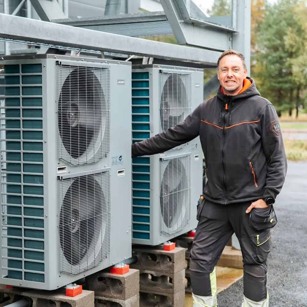 Ilmanvaihtokoneen huoltaja seisoo ilmanvaihtokoneen vieressä ennen ilmanvaihtohuollon aloittamista