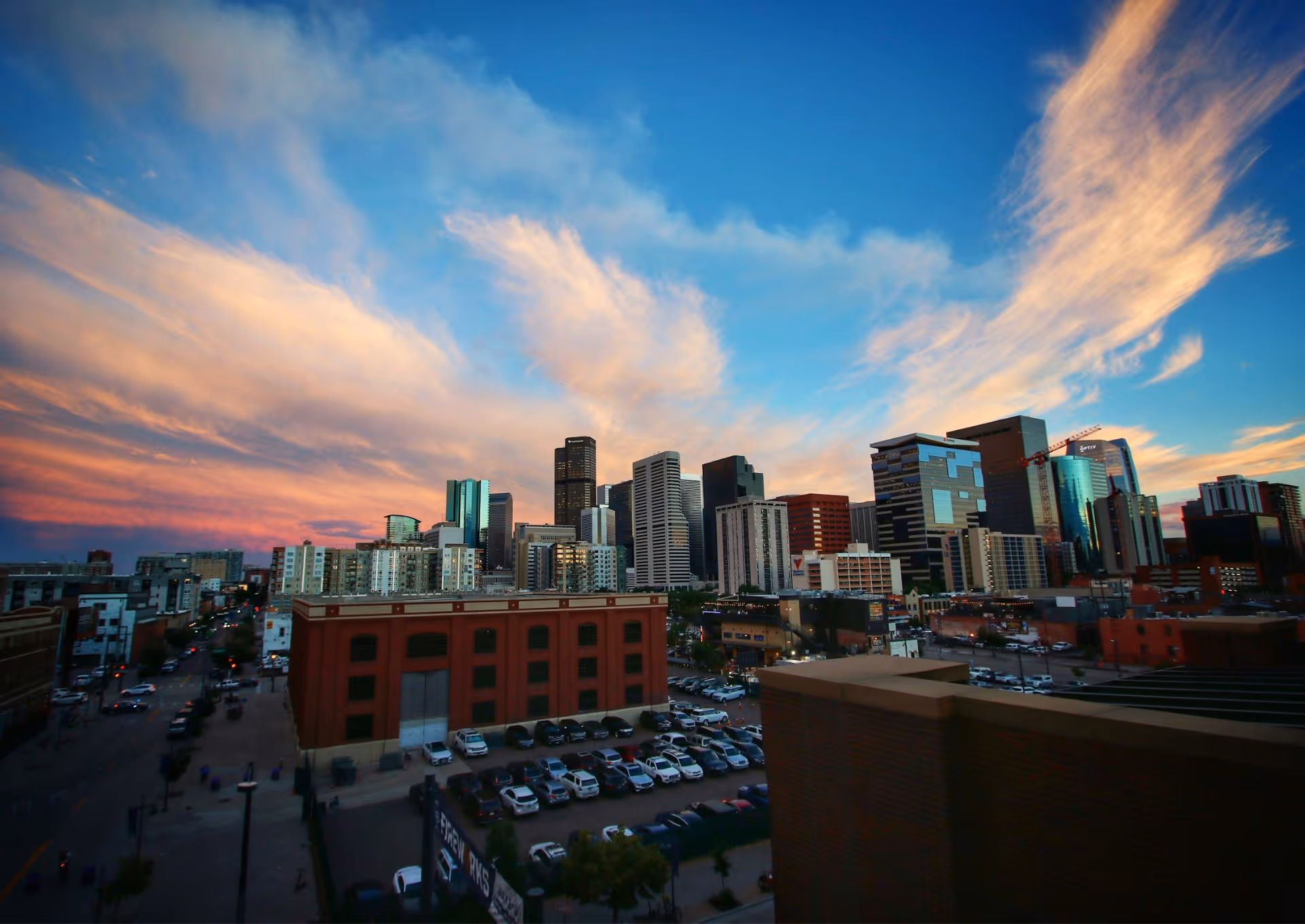 City skyline with modern skyscrapers and colorful sunset clouds in blue sky.