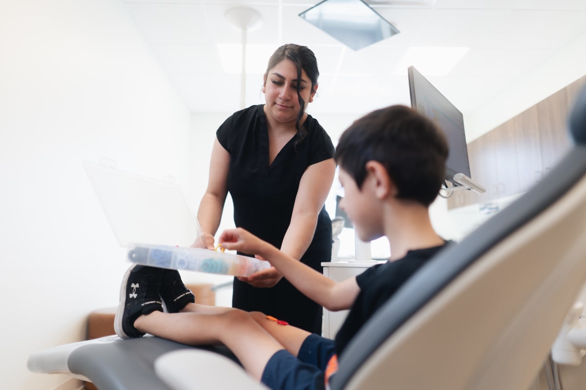 Pediatric dentist examining young child's teeth in dental chair during appointment
