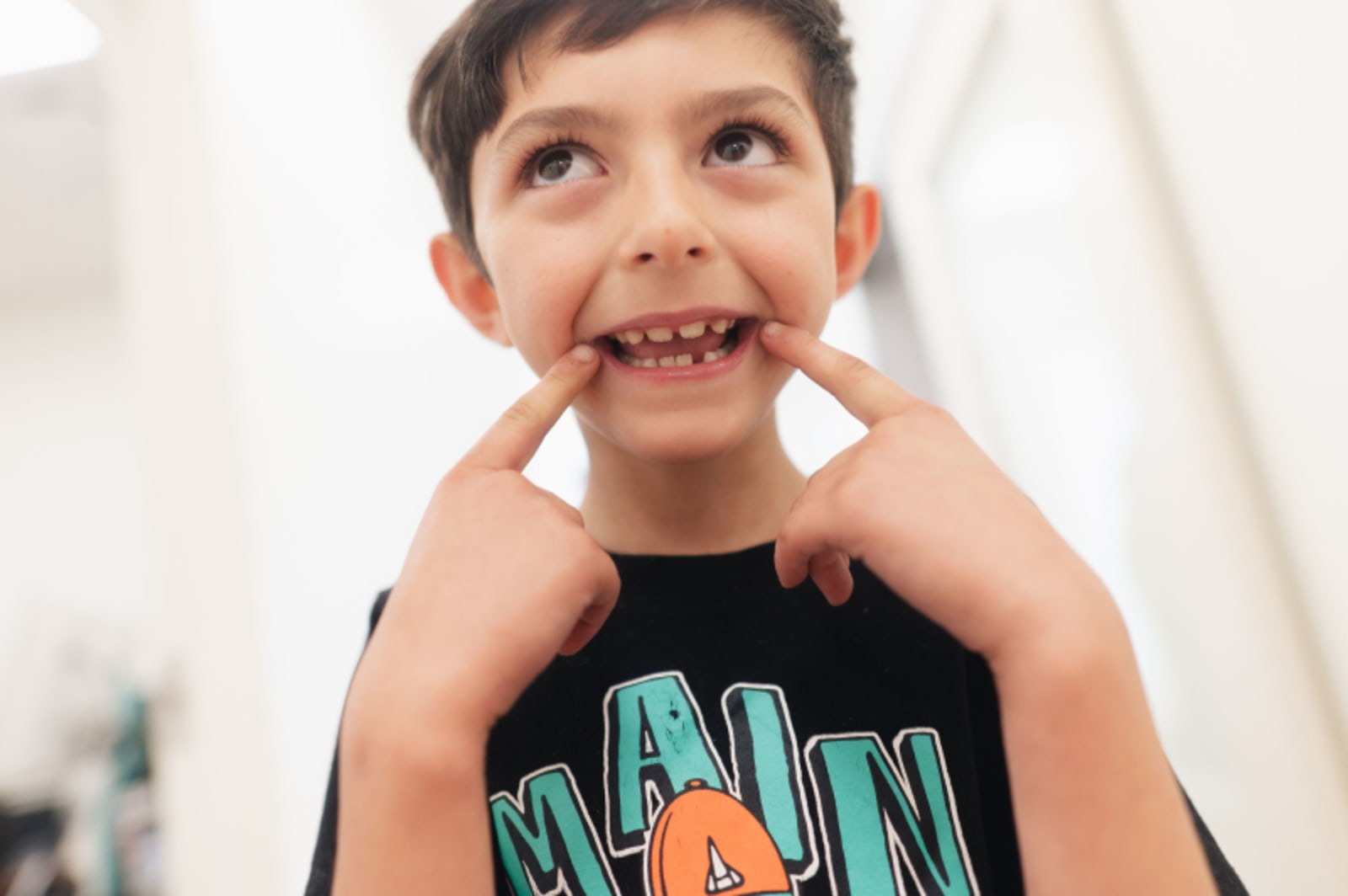 Young child smiling and pointing to his teeth showing healthy smile