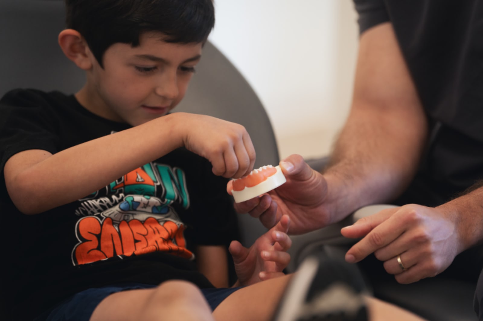 Dentist showing orthodontic aligner model to young child during consultation