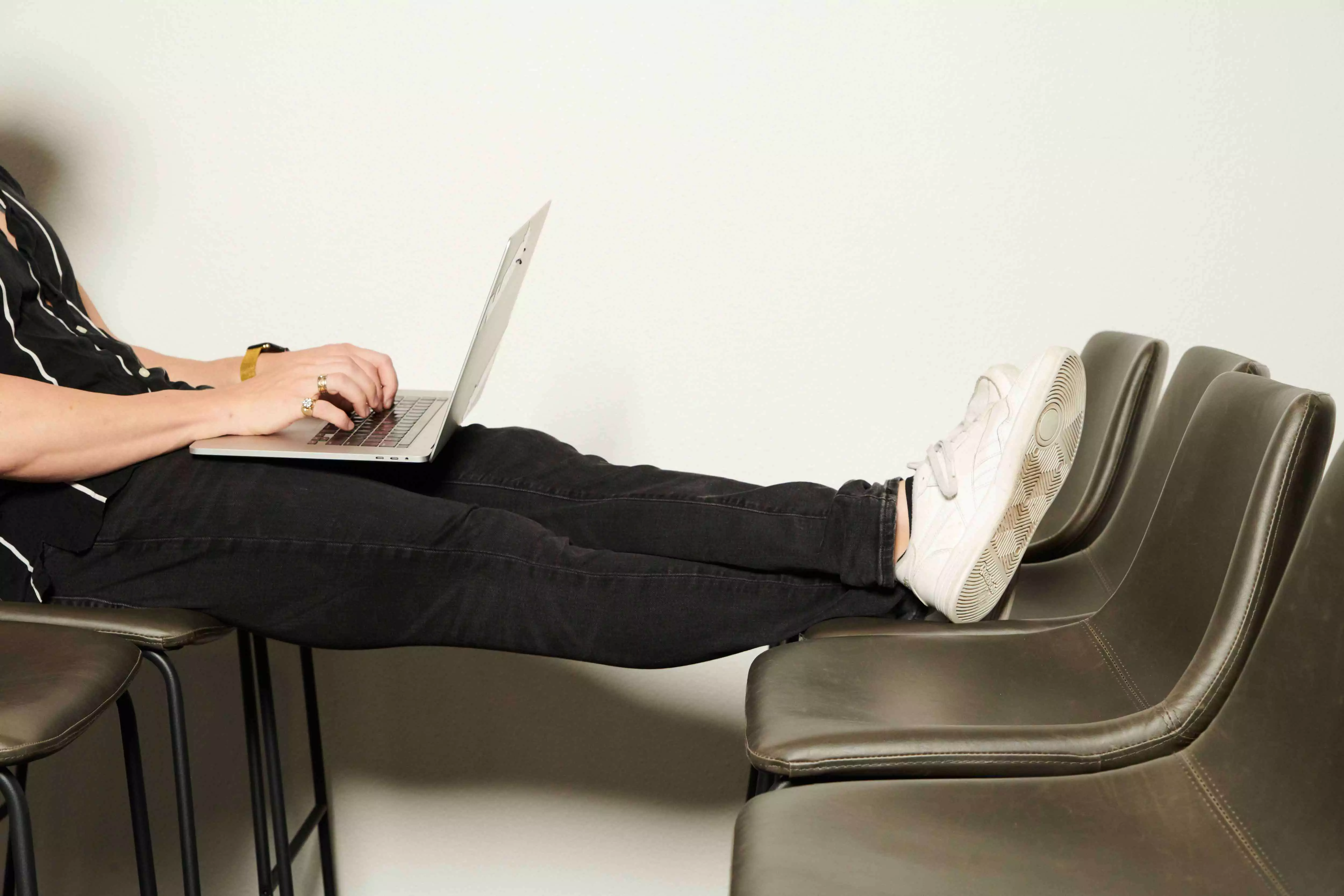 A man sitting on a chair using a laptop computer.