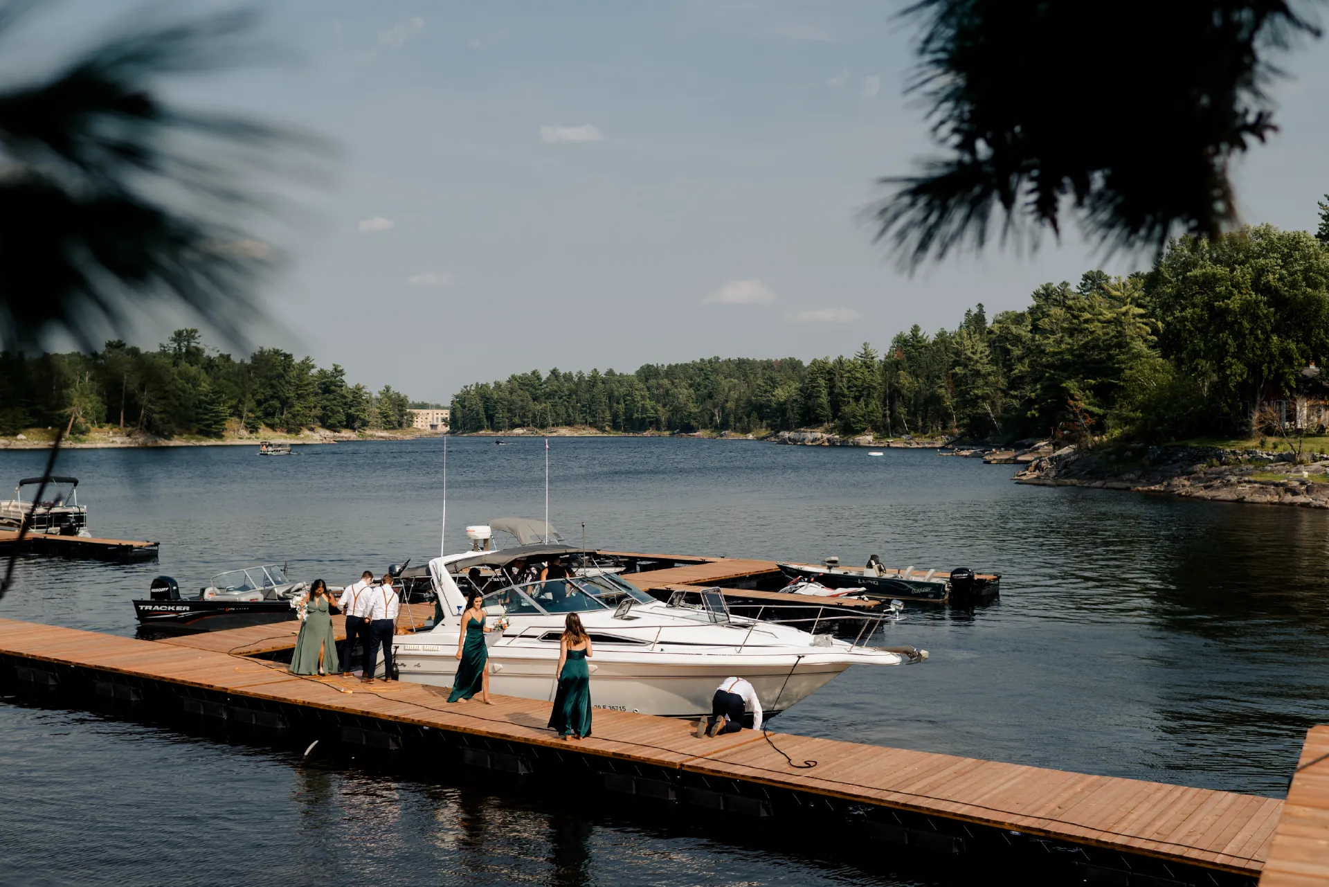 Wedding party standing on a wooden dock beside boats on the Winnipeg River.