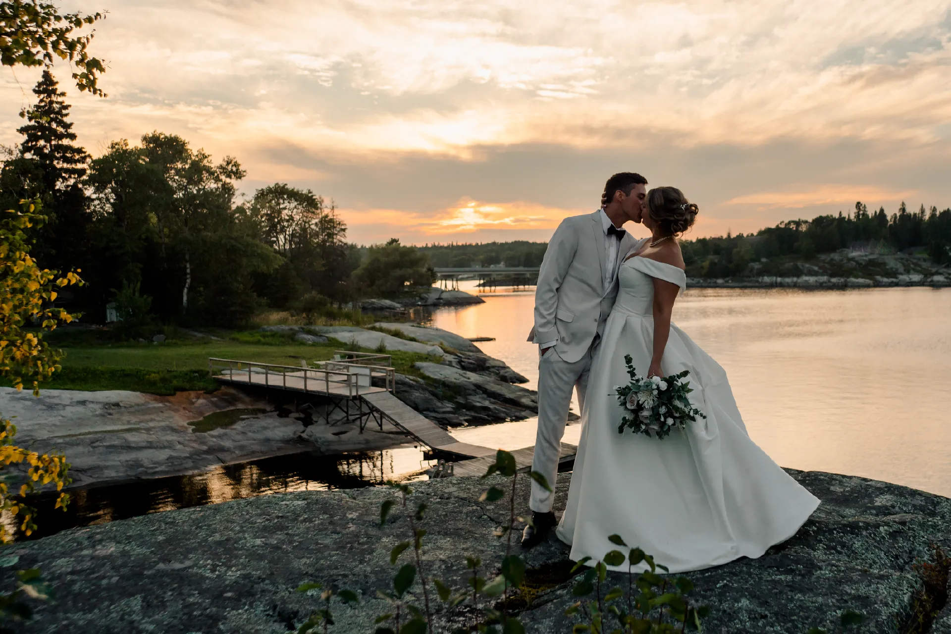 Couple standing by the Winnipeg River at sunset during a wedding at Perch Bay near Kenora